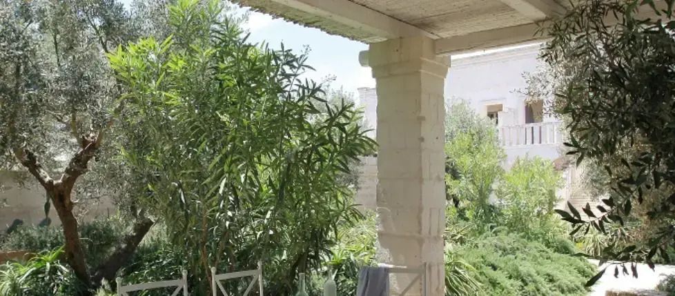 Überdachte Terrasse mit Blick auf üppiges Grün und einen entspannten Sitzbereich