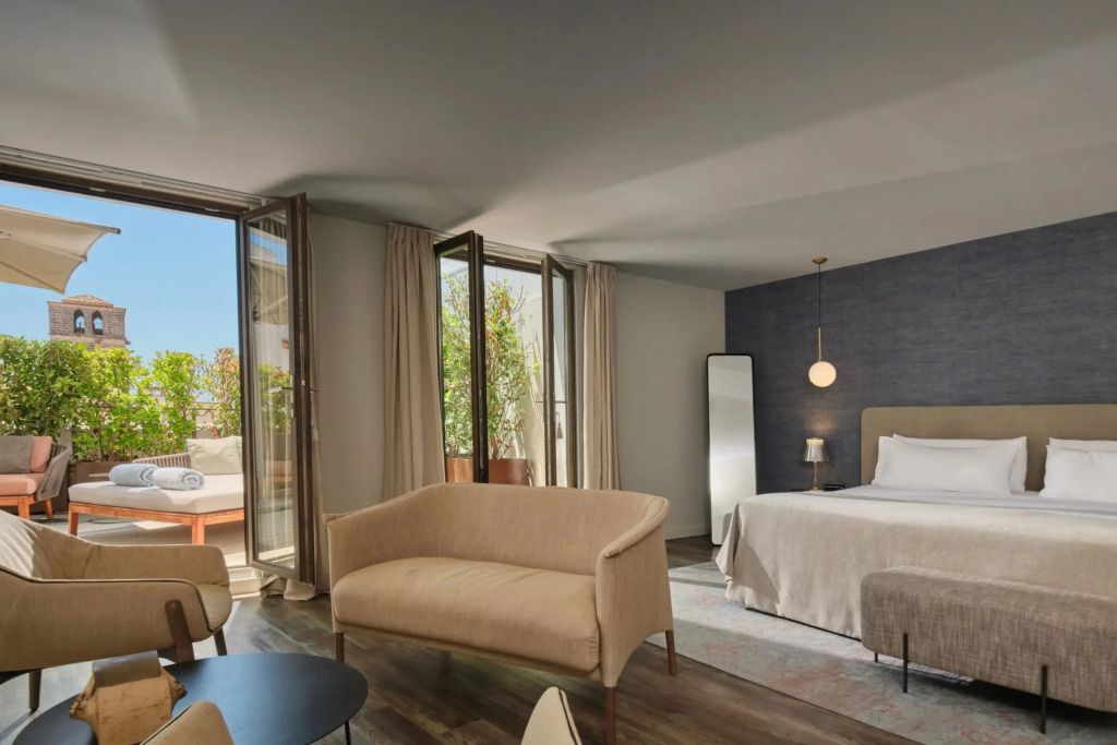 Suite mit bequemer Sofaecke und Zugang zu einer begrünten Terrasse