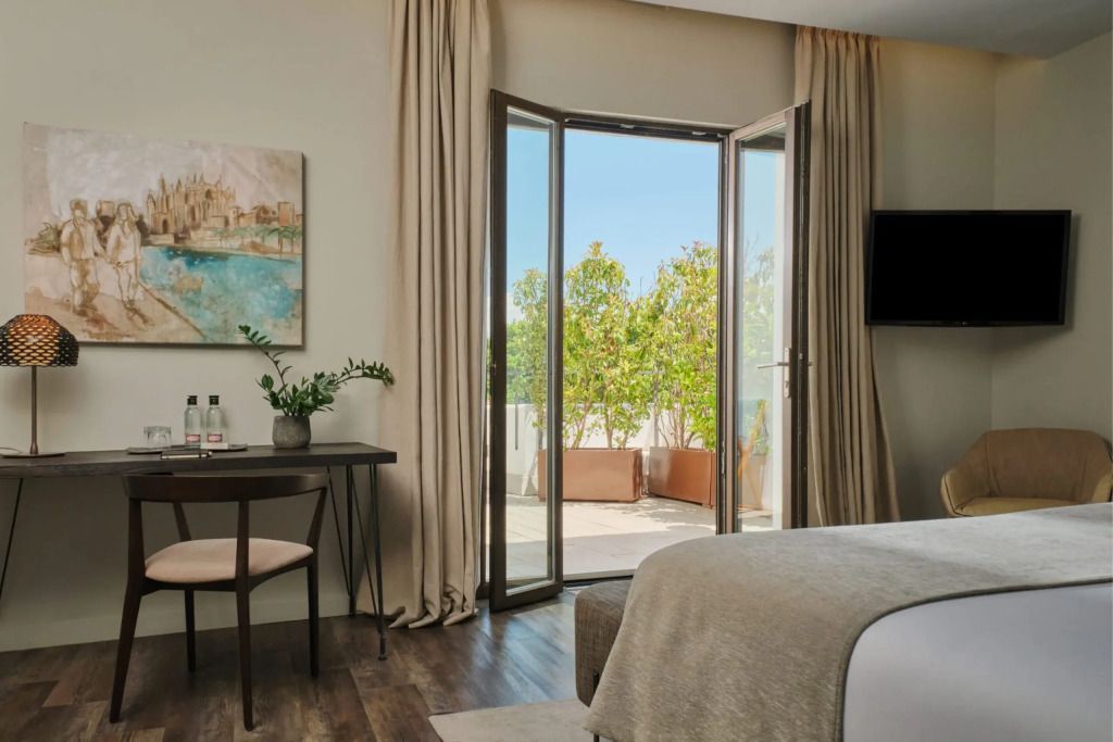 Elegantes Zimmer mit Doppelbett und offener Terrasse mit viel Grün.
