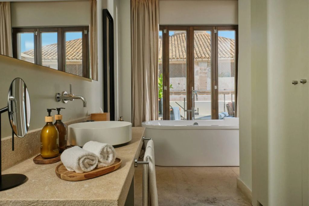 Luxuriöses Badezimmer mit freistehender Badewanne und Blick auf den Balkon.