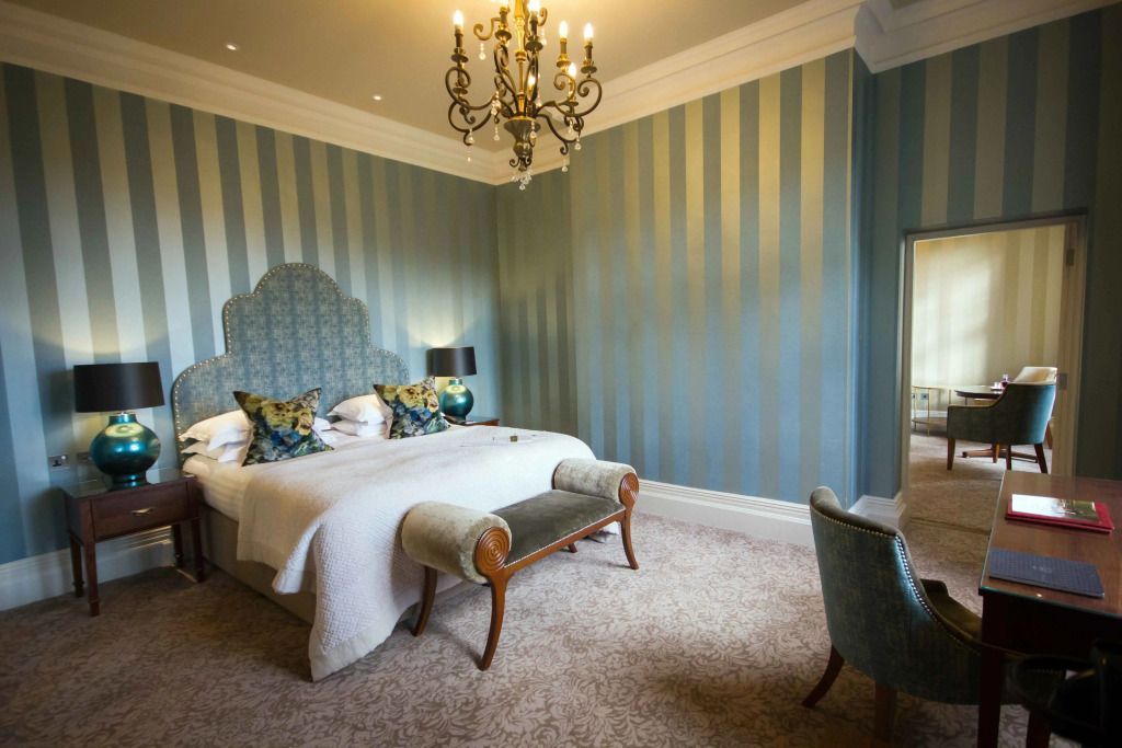 Elegantes Grand Doppelzimmer mit Kronleuchter und Doppelbett. Gestreifte Tapete.