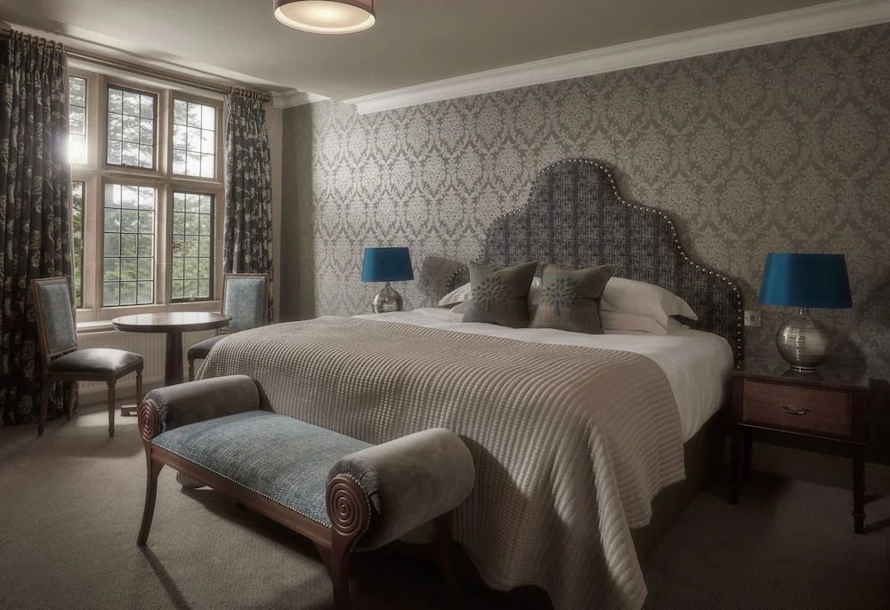 Doppelzimmer mit gepolstertem Bett und traditionellen Tapeten. Blick auf großes Fenster.