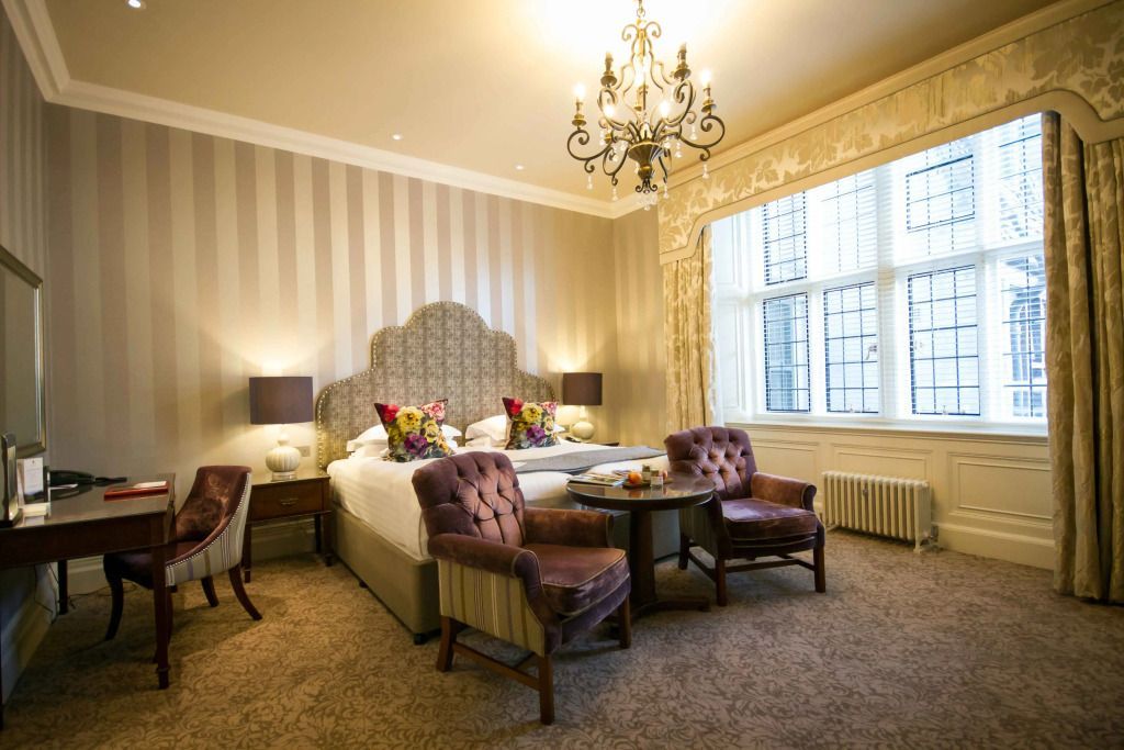 Komfortables Schlafzimmer mit gepolsterten Stühlen und einem Kronleuchter im Bovey Castle.