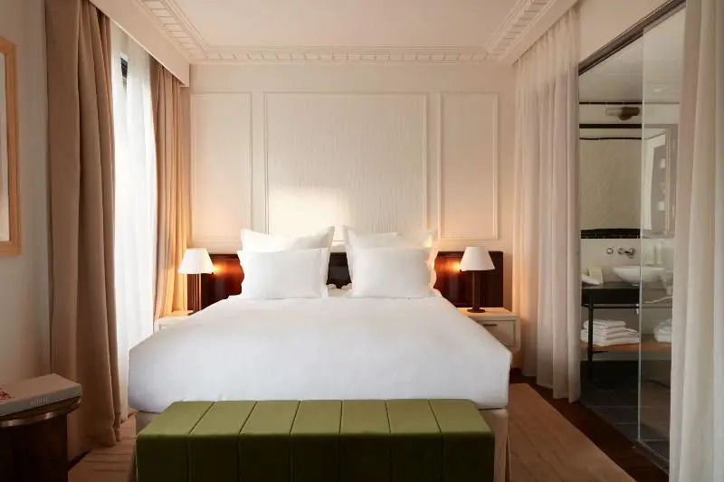 Luxuriöses Bett im Deluxe Zimmer mit sanfter Beleuchtung und klassischem Interieur.