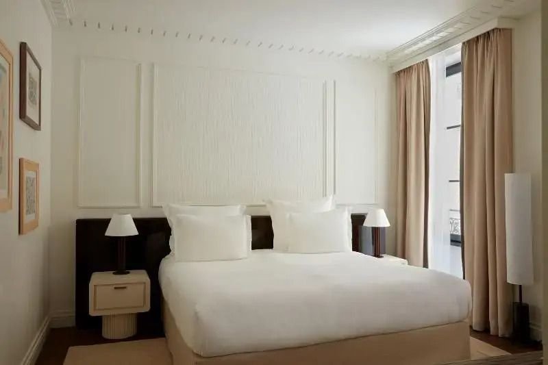 Helles Deluxe Zimmer mit großem Bett und eleganter Wandverkleidung.