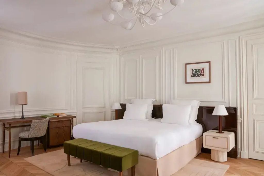 Elegante Junior-Suite mit großem Bett und grüner Bank vor klassischen Wandpaneelen