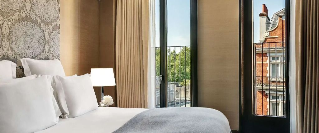 Helles Schlafzimmer mit Fenster und Blick auf grüne Bäume
