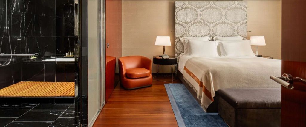 Elegante Suite mit Sessel, Beistelltisch und luxuriösem Bett in warmen Tönen