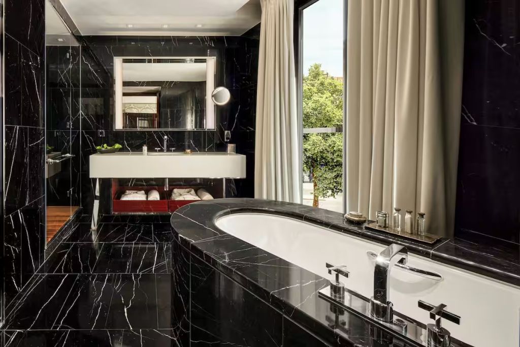 Modernes, elegantes Badezimmer mit schwarzem Marmor und großer Badewanne.