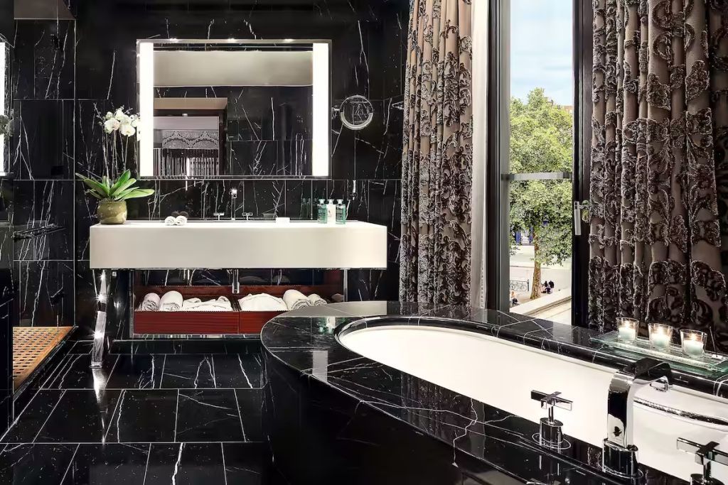 Badezimmer mit schwarzem Marmor, freistehender Badewanne und Tageslicht.