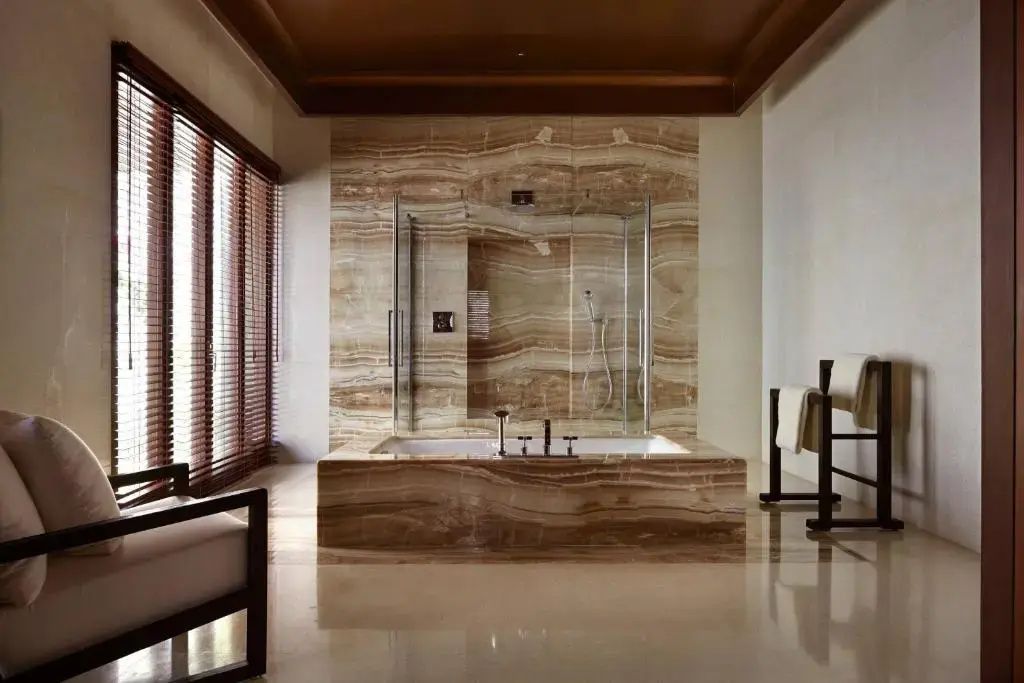 Luxuriöses Badezimmer aus feinstem Naturstein mit freistehender Badewanne und Regendusche.