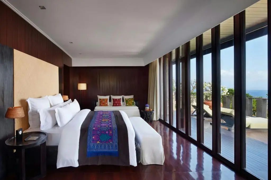 Elegantes Schlafzimmer mit Kingsize Bett, dunklem Holzfußboden und bodentiefen Fenstern.