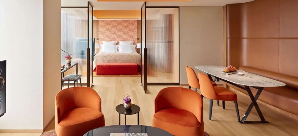 Geräumige Junior-Suite mit Doppelbett, modernen Möbeln und warmen Orangetönen