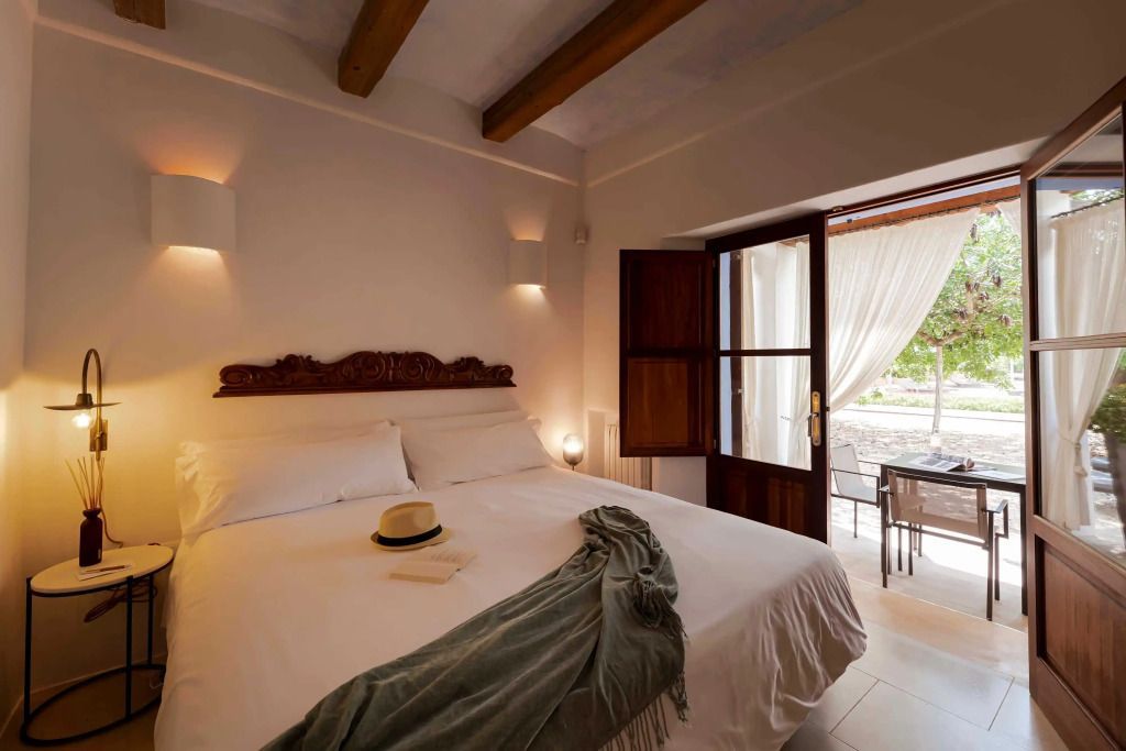 Helles Doppelzimmer mit Holzbalken und Balkonzugang im Ca Na Xica Hotel