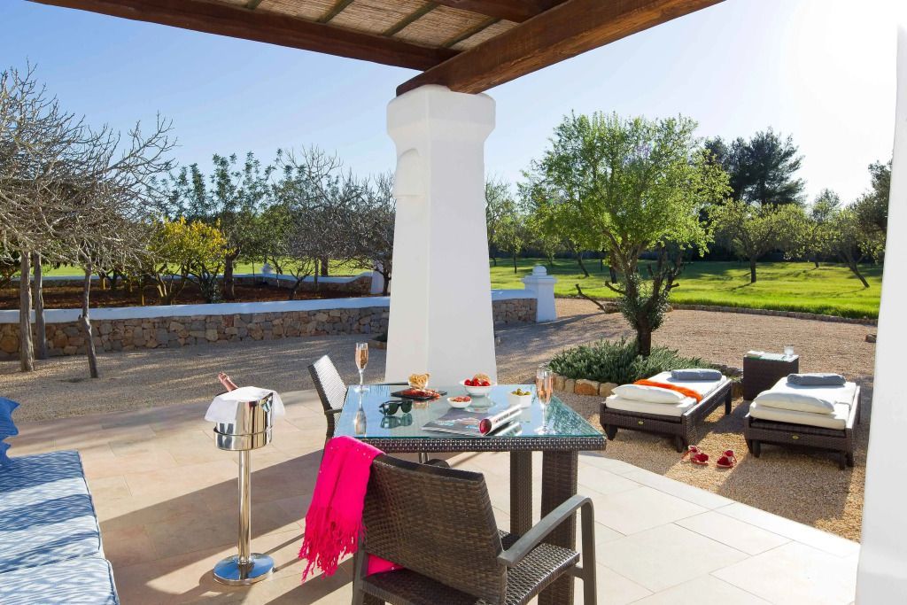 Terrasse mit Esstisch und Liegestühlen in einem malerischen Gartenambiente