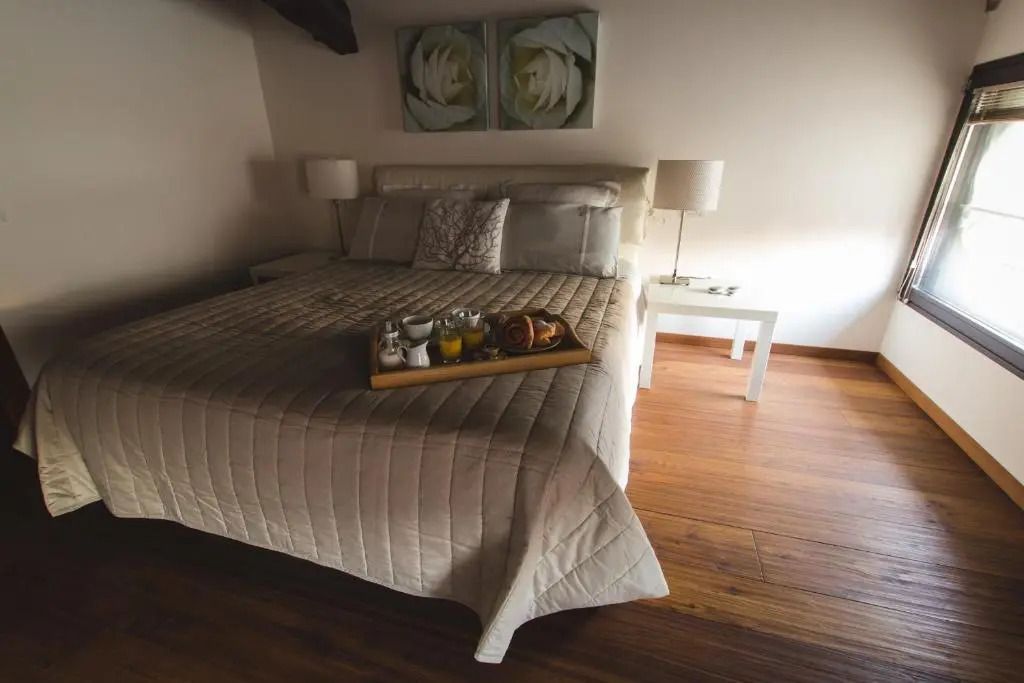 Junior-Suite mit Doppelbett und Tablett mit Frühstück unter Holzbalkendecke
