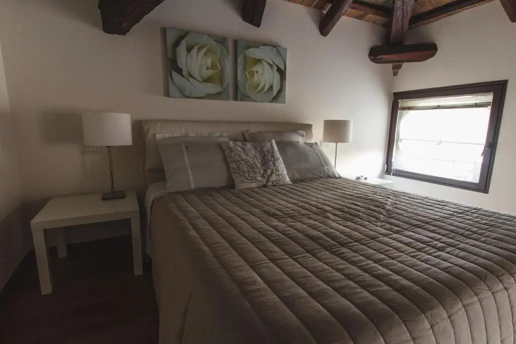 Komfortables Doppelbett in einer Junior-Suite mit Holzbalkendecke und Kunstwerk