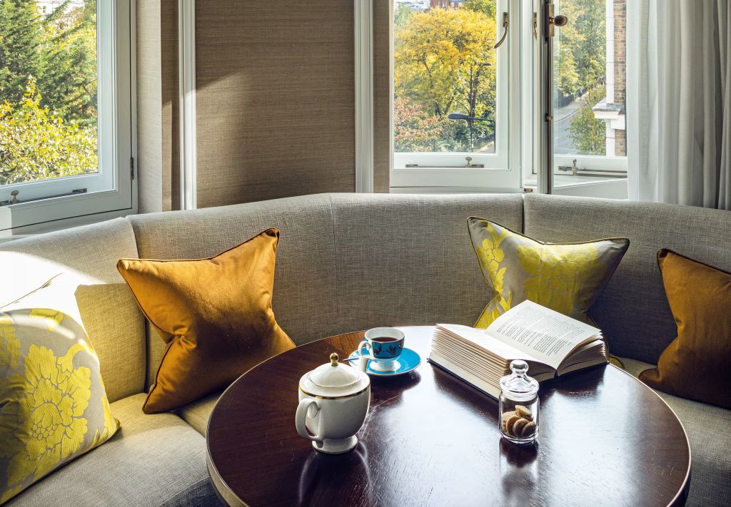 Tee und Lektüre auf einem Tisch vor dem Fenster mit Parkblick.