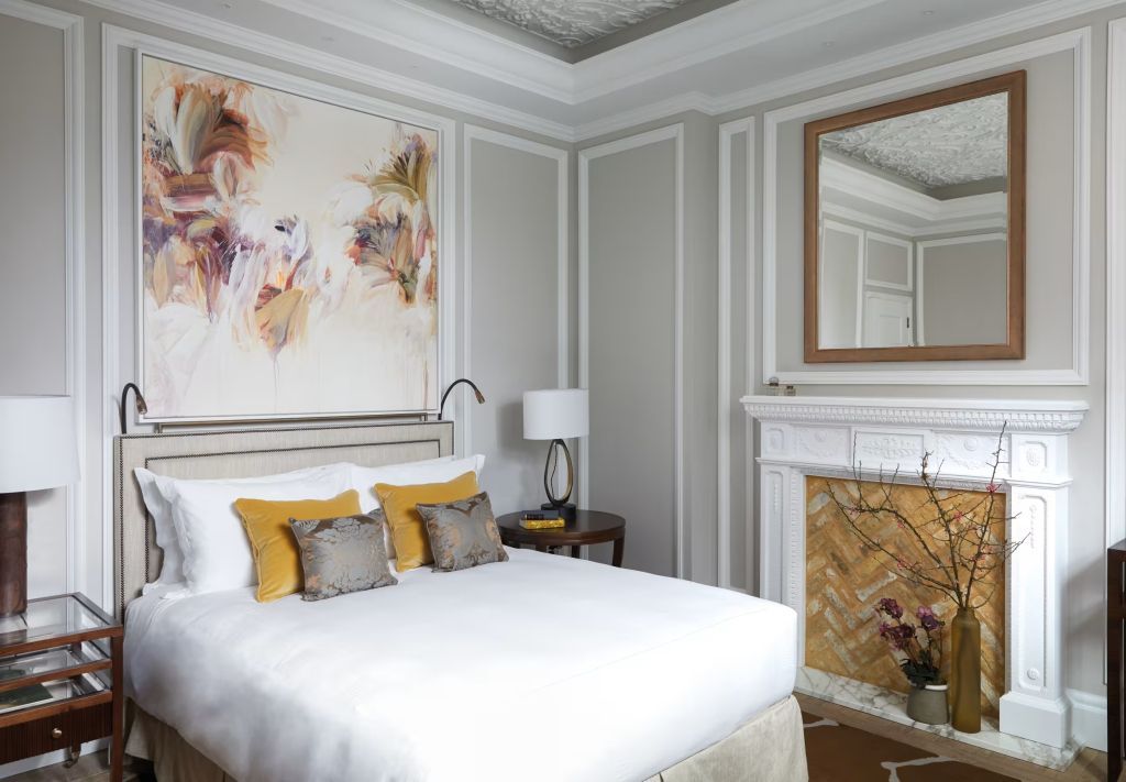 Elegantes Zimmer mit Doppelbett, kunstvoll dekoriertem Kamin und großem Gemälde.