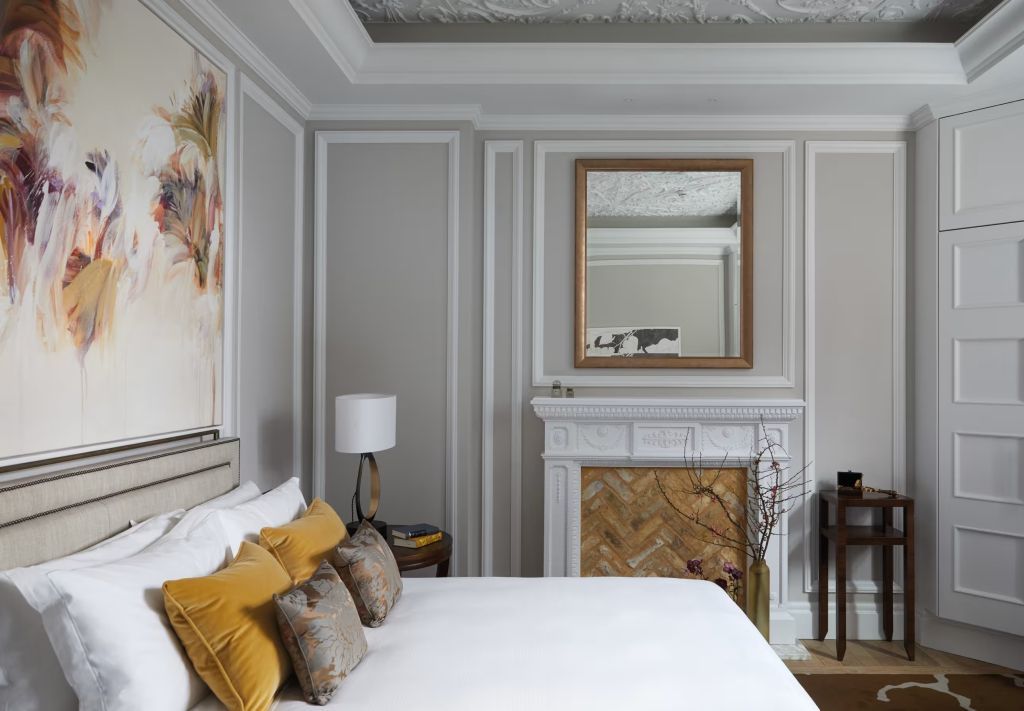 Geräumiges Schlafzimmer mit kunstvoll verziertem Kamin und luxuriösem Doppelbett.