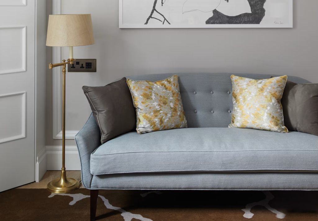Eleganter Sitzbereich im Zimmer mit grauem Sofa und dekorativen Kissen.