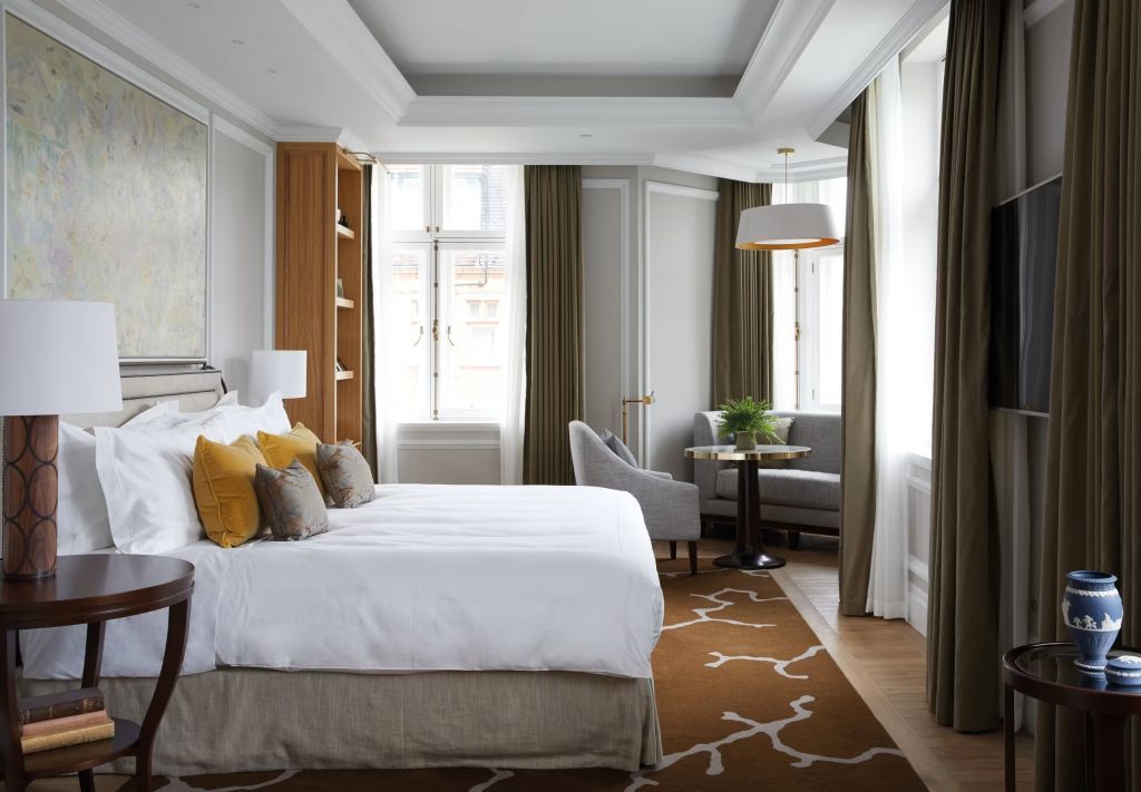 Lichtdurchflutetes Schlafzimmer mit großen Fenstern und gemütlicher Sitzecke in neutralen Tönen