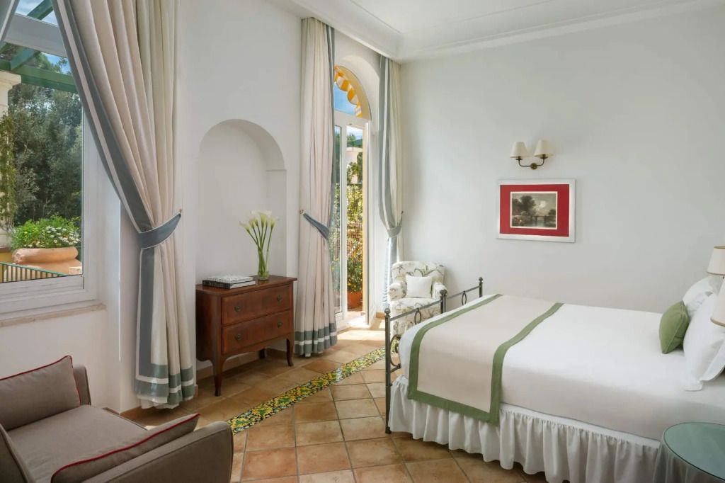 Elegantes Schlafzimmer mit Tageslicht durch hohe Fenster, Holzmöbel und helle Vorhänge