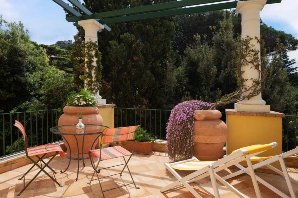 Garten-Terrasse mit blühender Vegetation, Terrakottafliesen und buntem Mobiliar