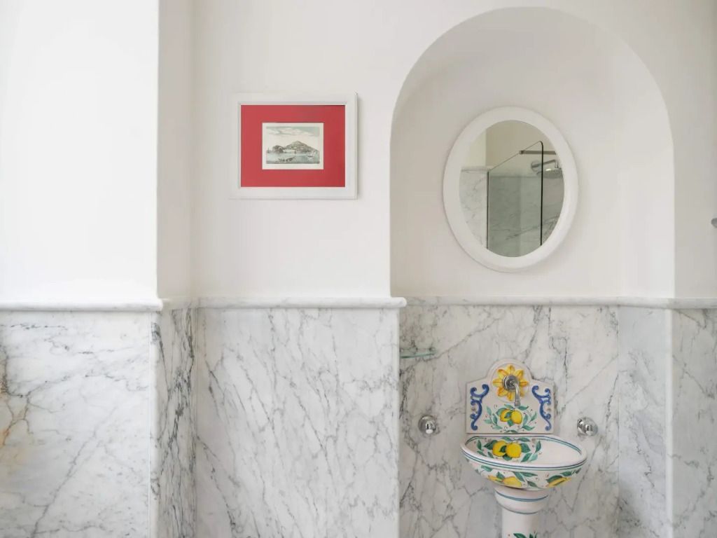 Stilvolles Badezimmer mit Marmorwänden und handbemaltem Waschbecken
