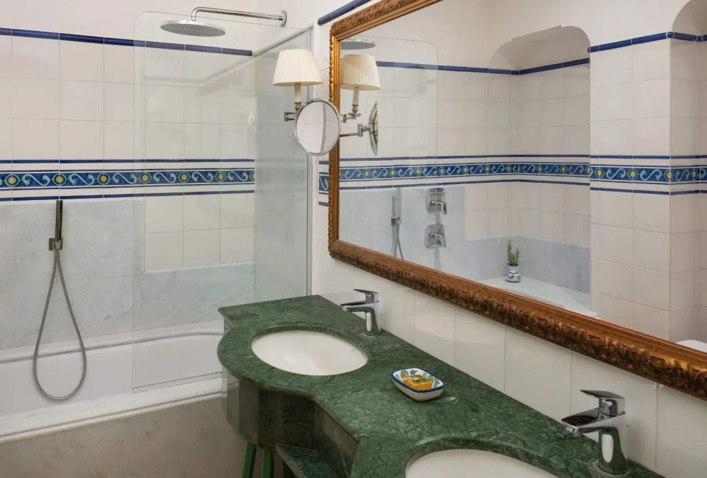 Badezimmer mit grünem Marmordoppelwaschbecken und großen Spiegeln.