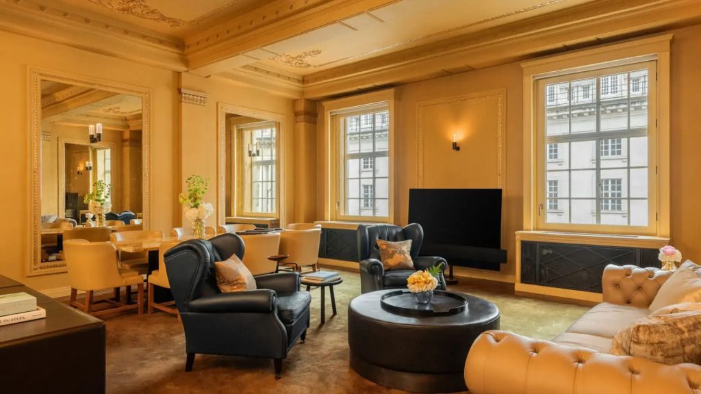 Geräumiges Wohnzimmer mit eleganten Sesseln, runden Tischen und großen Fenstern.