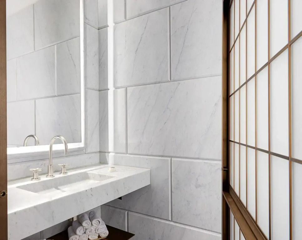 Luxuriöses Badezimmer mit Marmorverkleidung und großem Spiegel, elegantes Design.