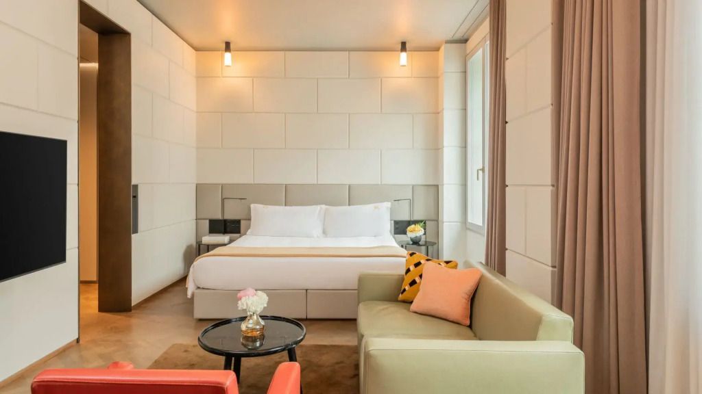 Elegante Suite mit Doppelbett, heller Sitzbereich und modernen Wandleuchten