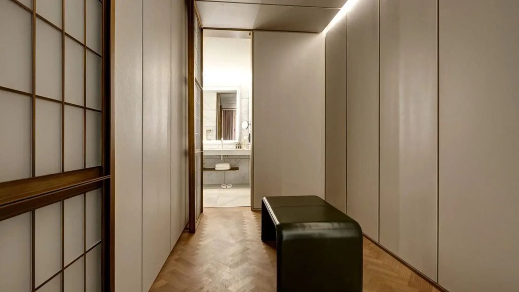 Schmaler Flur mit Sitzbank, führt zu einem eleganten Badezimmer