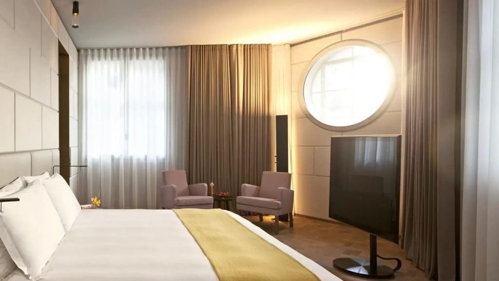 Luxuriöse Suite mit Doppelbett, zwei Sesseln und großem runden Fenster