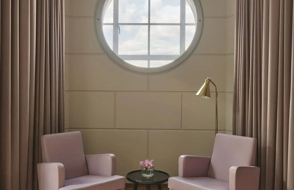 Zwei Sessel unter rundem Fenster mit Stehlampe in der Family Suite im Hotel Cafe Royal London