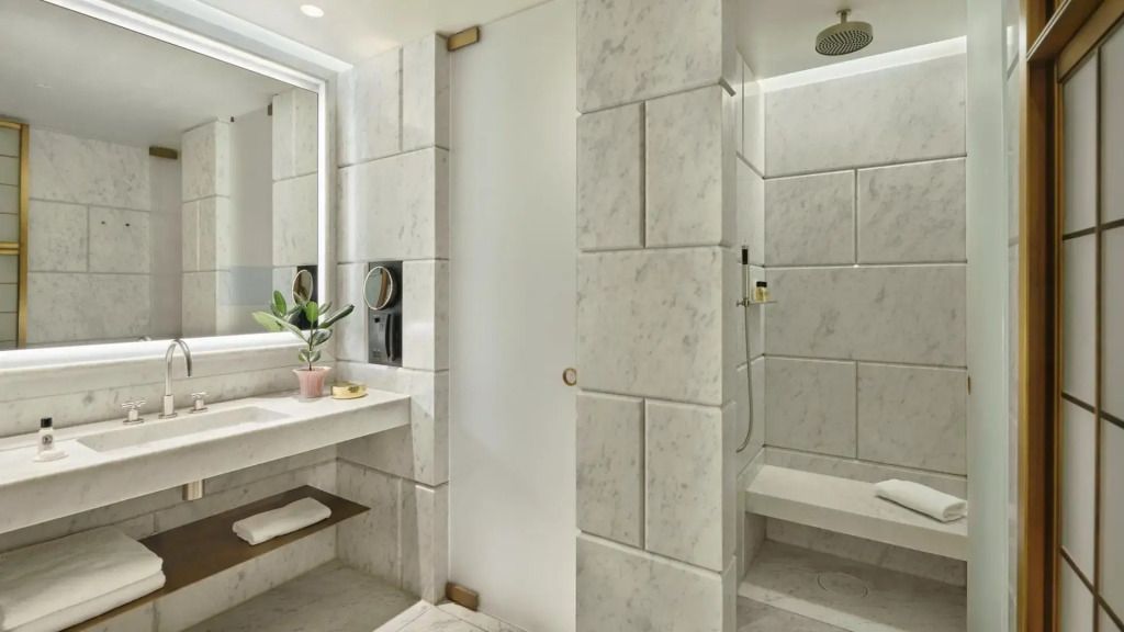 Modernes Badezimmer mit hellem Marmor, Dusche und Waschtisch im Hotel Cafe Royal London.