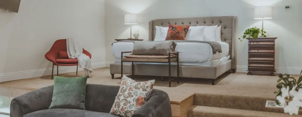Elegantes Schlafzimmer mit großem Doppelbett und stilvollen Kissen in warmen Farben