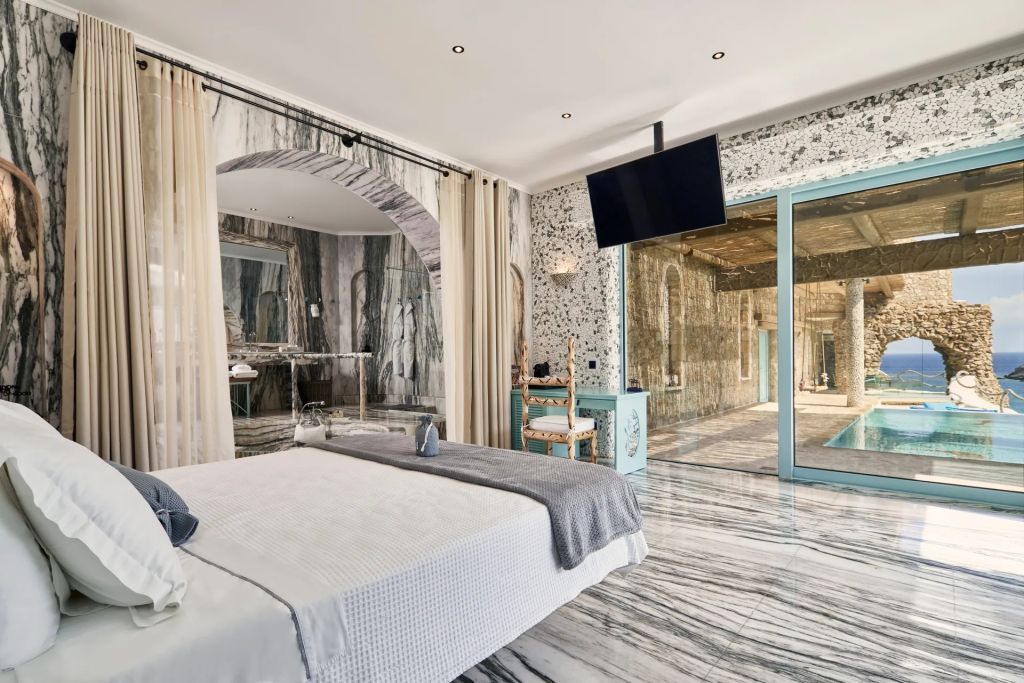 Luxuriöses Schlafzimmer mit Marmorakzenten und Blick auf einen privaten Poolbereich