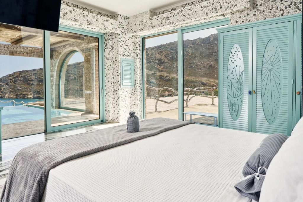 Helles Schlafzimmer mit großen Fenstern und Blick auf die Landschaft