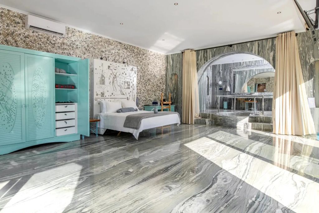 Helles Zimmer mit Marmorboden, Doppelbett und türkisfarbenen Möbeln in der Deluxe Suite.