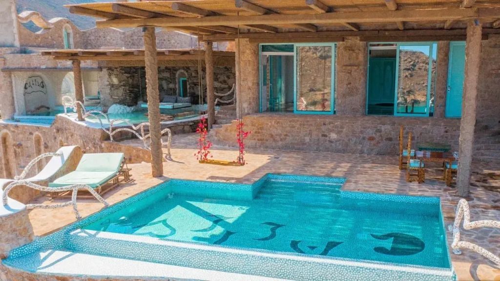 Privater Poolbereich mit Liegen vor einer Suite aus Naturstein.