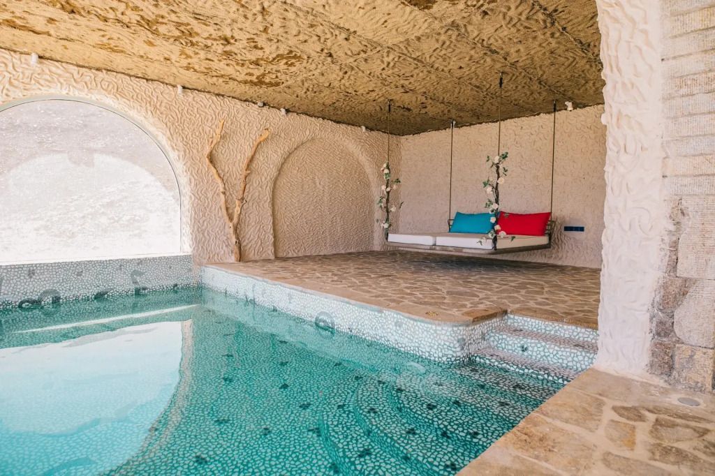 Gemütlicher Indoor-Poolbereich mit stilvollem Hängesofa und dekorativen Elementen