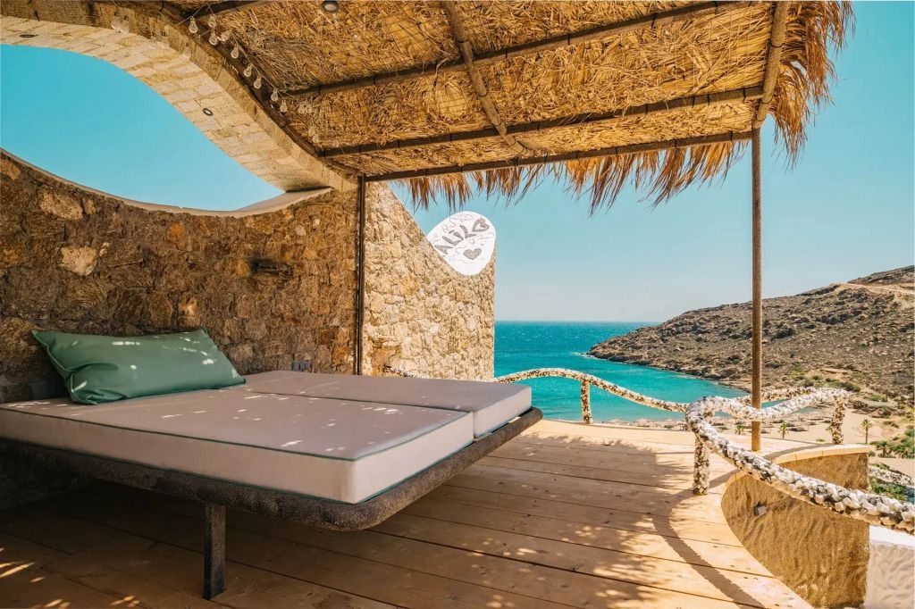 Terrasse mit Liegen und atemberaubendem Blick auf das Meer unter strohgedecktem Dach