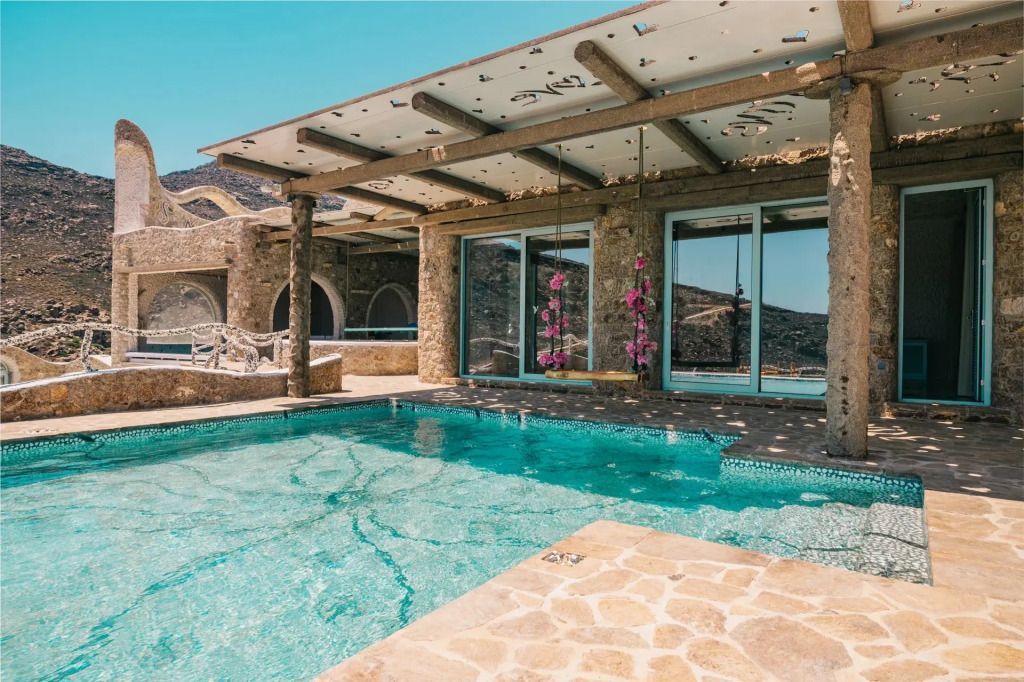 Privater Poolbereich mit glitzerndem Wasser und Steinarchitektur unter klarem Himmel