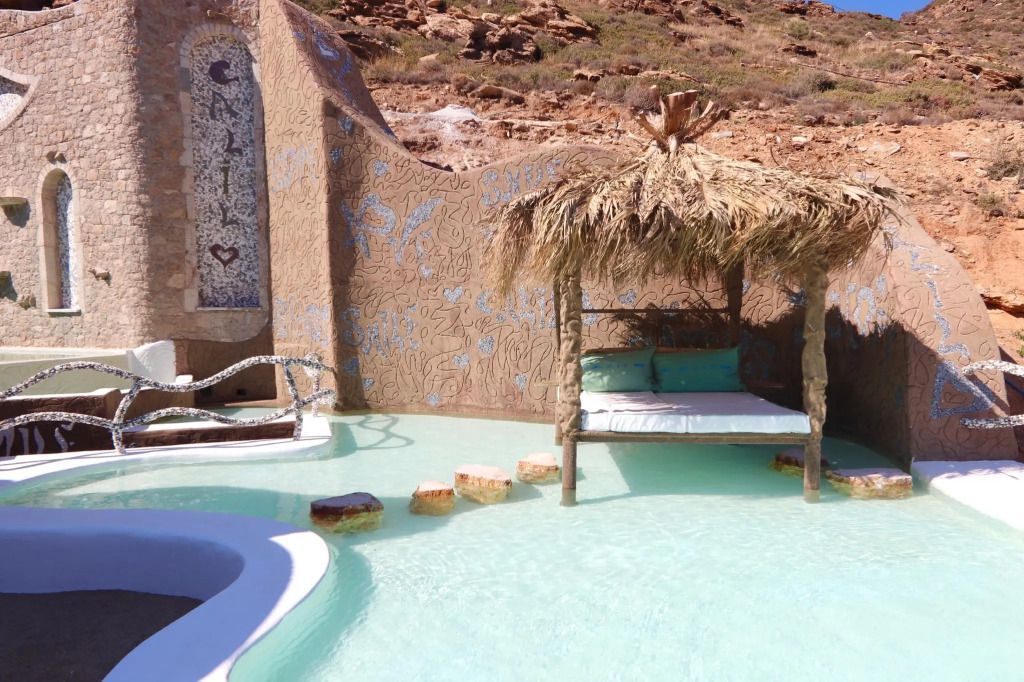 Gemütliche Liegefläche am Pool mit Strohüberdachung und dekorativer Wandornamente