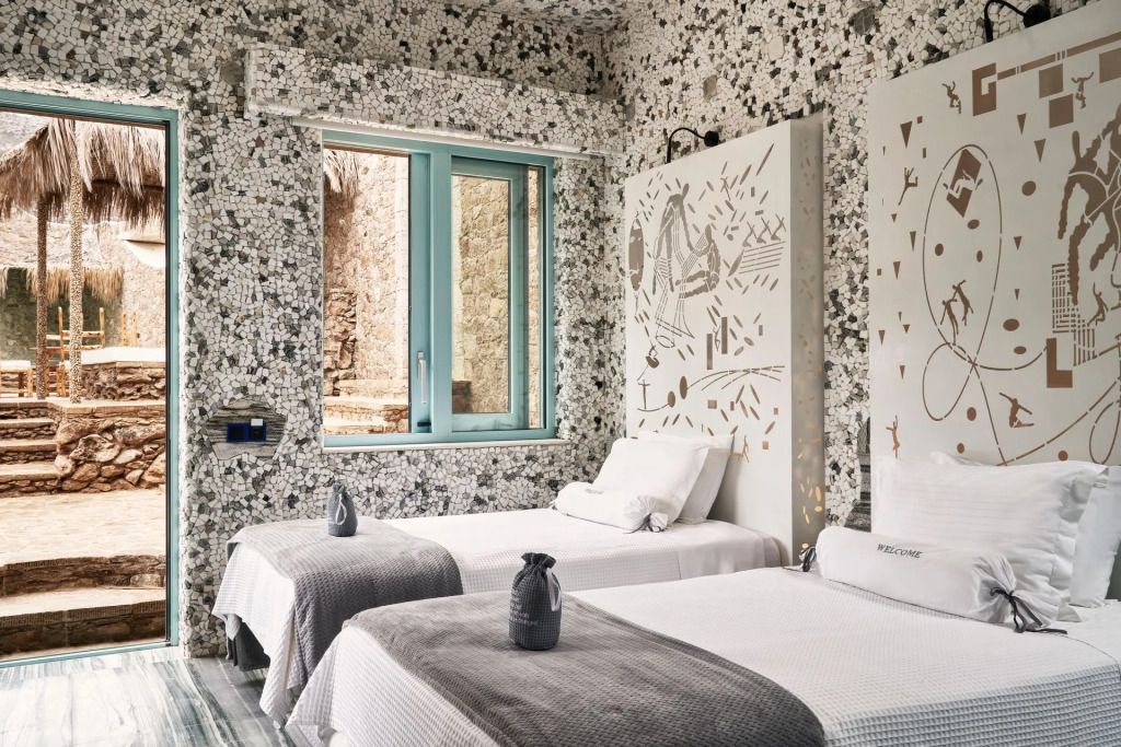 Suite mit zwei Einzelbetten und moderner Wandkunst in marmoriertem Raum.