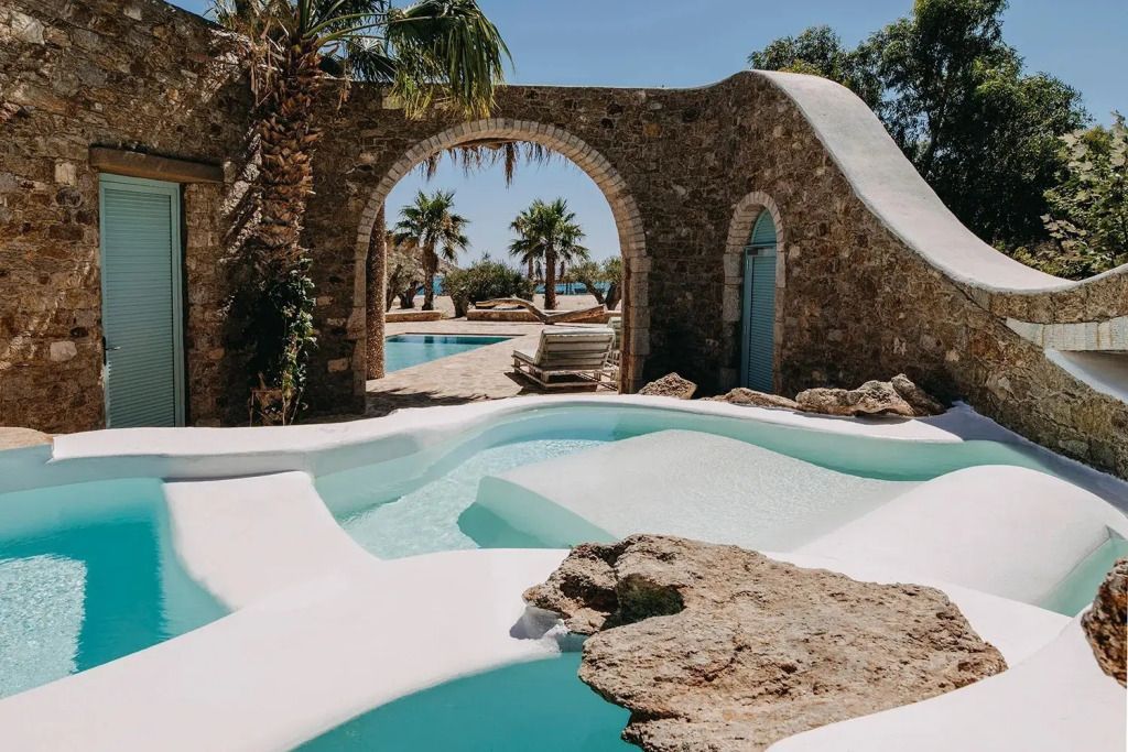 Exotischer Pool-Bereich mit Palmen und Natursteinmauern im Hotelgarten