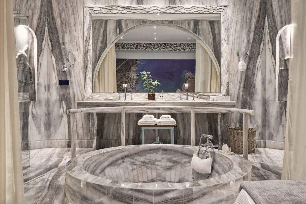 Großzügiges Marmorbadezimmer mit eingelassener Badewanne und Spiegelwand