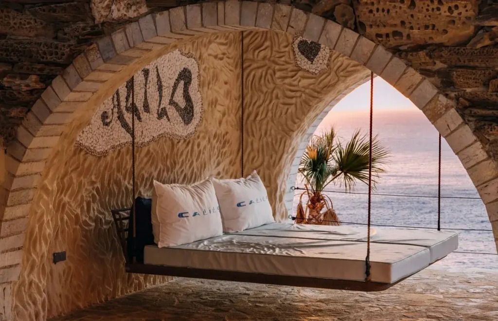 Schwebendes Bett mit Blick auf das Meer bei Sonnenuntergang in der Suite